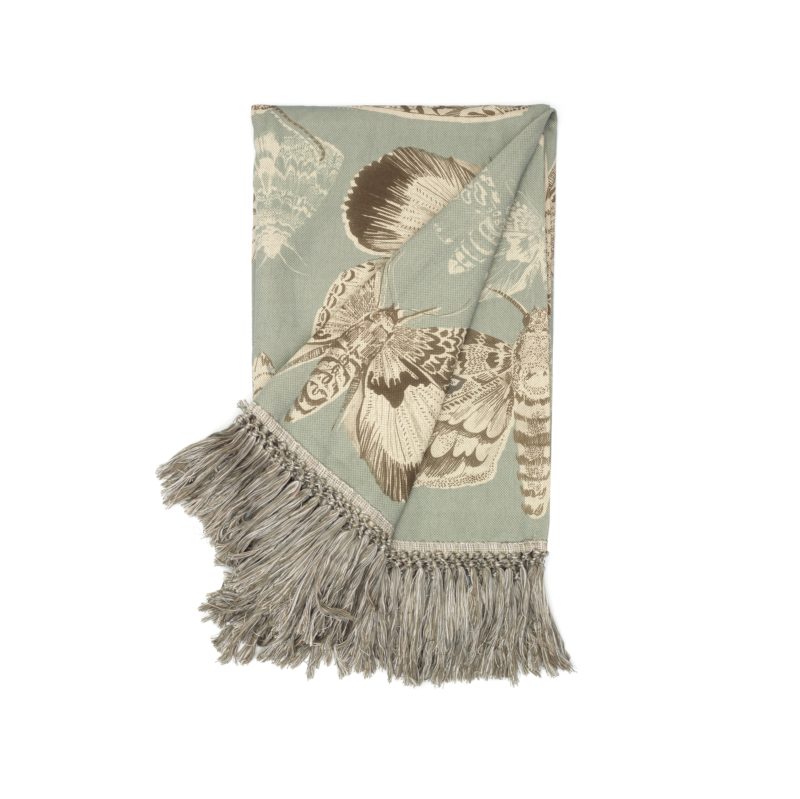 Voyage Maison Nocturnal Seathistle Throw moths on a duck egg blue background with gresy tassel edge