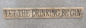 A Rustic Wooden Plaque quoting Let The Drinking Be Gin, engraved in capital letters