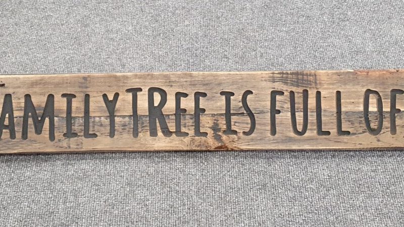 A Rustic Wooden Plaque quoting Our family tree is full of nuts, engraved in capital letters
