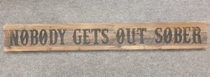 A Rustic Wooden Plaque quoting Nobody Gets out Sober, engraved in capital letters